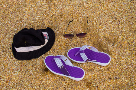 Pair of flip flops, hat and sunglasses on a sandy sea beach. Summer vacation conceptの写真素材