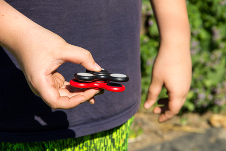 Boy playing with two fidget spinner stress relieving toys outdoorの写真素材