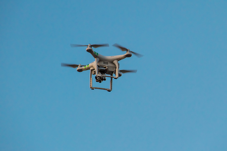 Quadcopter drone with camera hovering in blue skyの写真素材