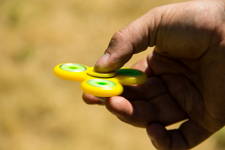 Man playing with fidget spinner stress relieving toy outdoorの写真素材