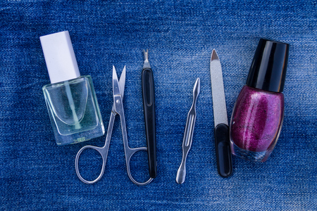 Basic set of manicure tools on jeans background. Nail and cuticle scissors, cuticle trimmer, nail file, nail polishの写真素材