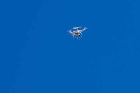 Quadcopter drone with camera hovering in blue skyの写真素材