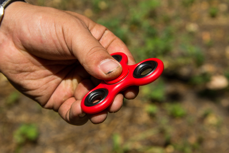 Man playing with fidget spinner stress relieving toy outdoorの写真素材