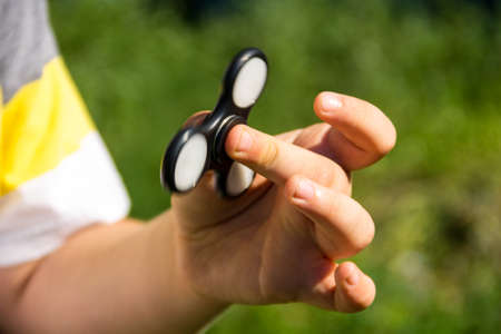 Boy playing with fidget spinner stress relieving toy outdoorの写真素材