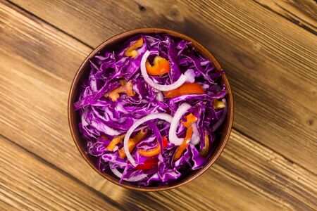 Red cabbage salad in ceramic bowl on wooden table. Top viewの写真素材