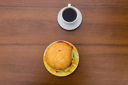 Delicious hamburger and cup of coffee on wooden table. Top viewの写真素材