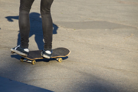 Skateboarder legs riding skateboard at skatepark