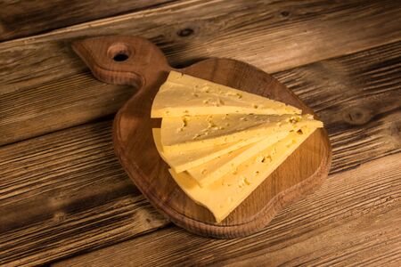 Sliced cheese on cutting board on wooden table