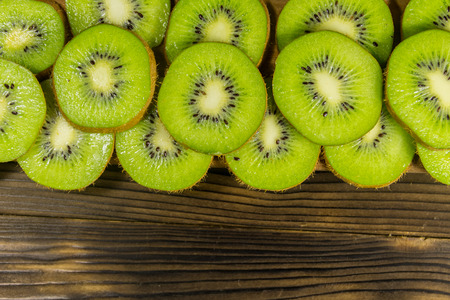 Sliced kiwi fruits on wooden table. Top view, copy spaceの写真素材
