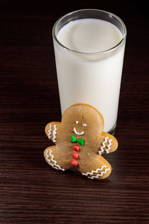 Gingerbread man and glass of milk on dark wooden table. Christmas conceptの写真素材