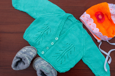 Baby clothes, booties and soother on wooden background. Kit for newbornsの写真素材