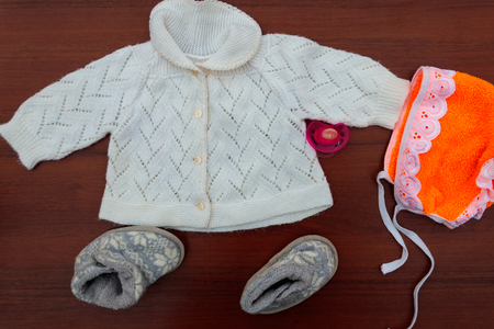 Baby clothes, booties and soother on wooden background. Kit for newbornsの写真素材