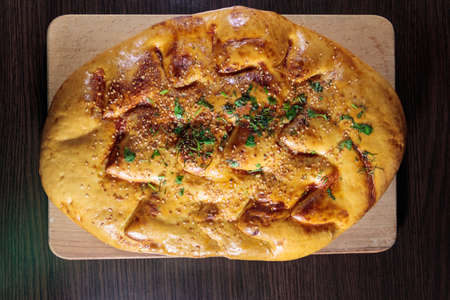 Pita bread on cutting board on wooden table. Top view