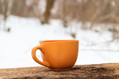 Orange cup of coffee on the background of the winter forestの写真素材