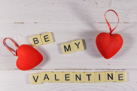 Red hearts and "Be my Valentine" text on white wooden background. Top viewの写真素材