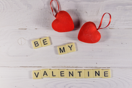 Red hearts and "Be my Valentine" text on white wooden background. Top viewの写真素材