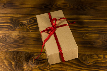 Cardboard gift box with red ribbon on wooden tableの写真素材
