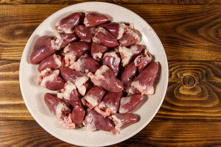 Raw chicken hearts on wooden table. Top viewの写真素材