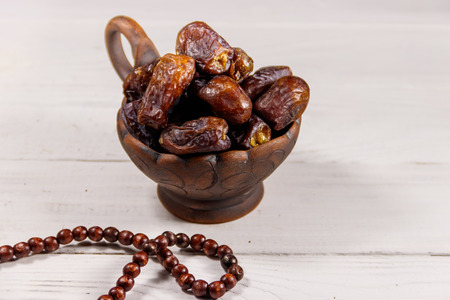 Dates fruit and rosary on white wooden table. The Muslim feast of the holy month of Ramadanの写真素材