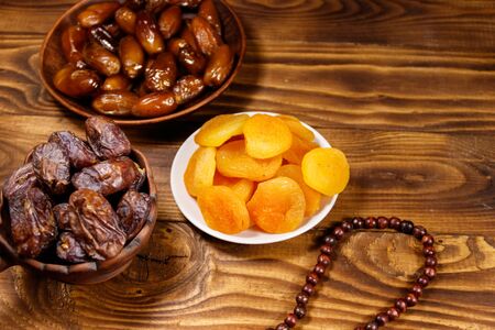 Dried apricots and dates fruit with wooden rosary on wooden table. The Muslim feast of the holy month of Ramadanの写真素材
