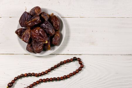 Dates fruit and rosary on white wooden table. Top view. The Muslim feast of the holy month of Ramadanの写真素材