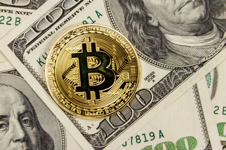 Golden bitcoin on hundred dollar bills backgroundの写真素材