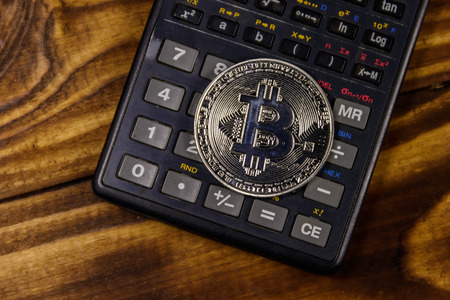 Silver bitcoin and calculator on wooden deskの写真素材