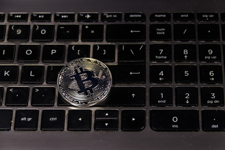 Silver bitcoin on laptop keyboard. Cryptocurrency virtual money