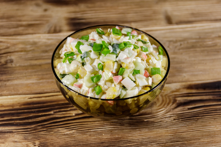 Salad with crab sticks, sweet corn, cucumber, eggs, rice and mayonnaise on wooden tableの写真素材