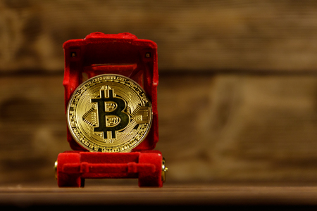 Golden souvenir coin bitcoin in car-shaped gift box for jewelry on wooden backgroundの写真素材