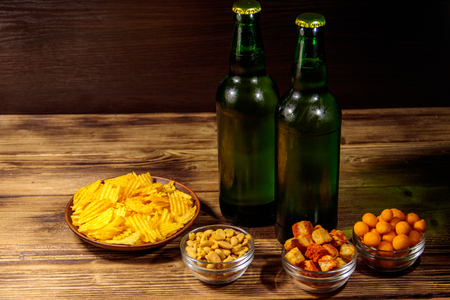 Bottles of beer and various snacks for beer on wooden tableの写真素材