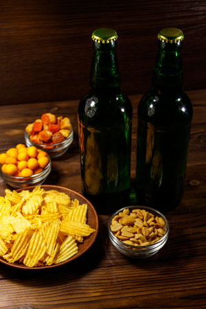 Bottles of beer and various snacks for beer on wooden tableの写真素材