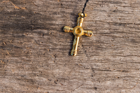 Small Christian golden cross on rustic wooden background. Religion conceptの写真素材