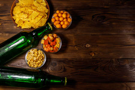 Bottles of beer and various snacks for beer on wooden table. Top view, copy spaceの写真素材