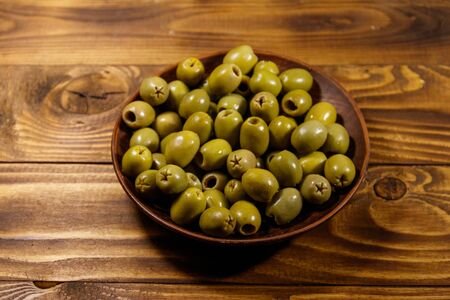 Plate with green olives on wooden tableの写真素材