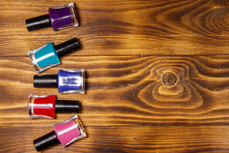 Set of nail polish bottles on wooden background. Top view, copy spaceの写真素材