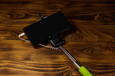 Monopod for selfie with smart phone on wood desk. Selfie stick with smartphone on wooden backgroundの写真素材