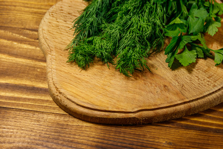 Fresh green dill and parsley on cutting board on wooden tableの写真素材