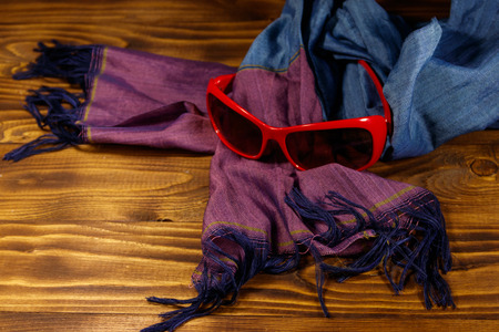 Red sunglasses and summer scarf on wooden background. Women's fashion accessories. Summer vacation and travel conceptの写真素材