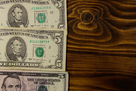 Five dollars banknotes on wooden background. Top view