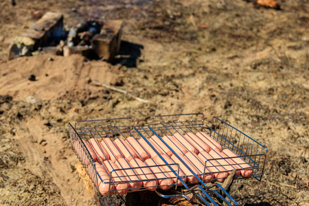 Sausages in barbecue grill near campfire ready for grillingの写真素材