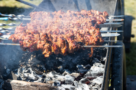 Grilled kebab cooking on metal skewer. Roasted meat cooked at barbecue.Traditional eastern dish, shish kebab. Grill on charcoal and flame, picnic, street foodの写真素材