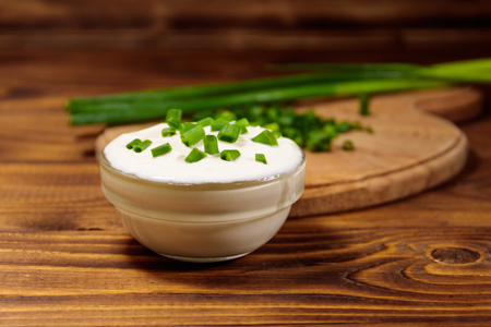 Sour cream and green onion on wooden tableの写真素材