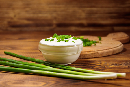 Sour cream and green onion on wooden tableの写真素材