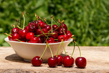 Bowl with fresh cherry on rustic wooden table outdoorの写真素材