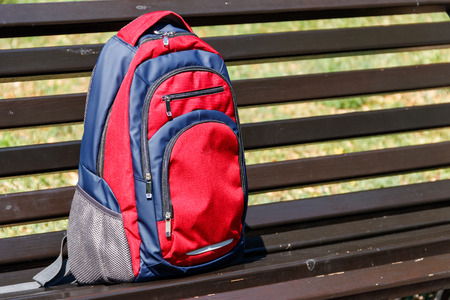 Backpack on wooden bench in city parkの写真素材