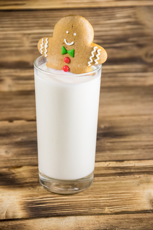 Gingerbread man in glass of milk on dark wooden table. Christmas conceptの写真素材
