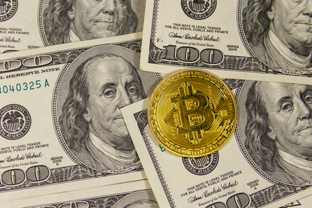 Golden bitcoin on hundred dollar bills backgroundの写真素材