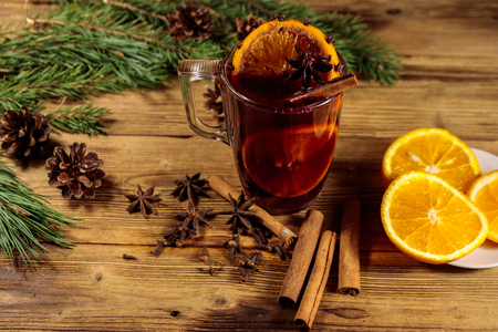 Christmas mulled wine with spices and fir tree branches and cones on wooden tableの写真素材