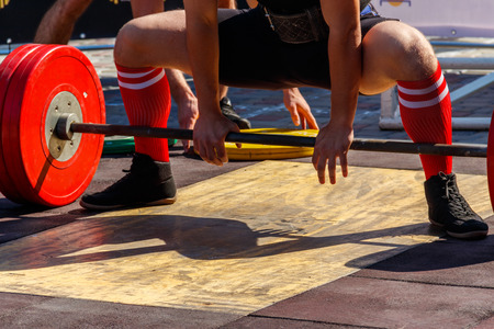 Powerlifter preparing for deadlift of barbell during competition of powerliftingの写真素材